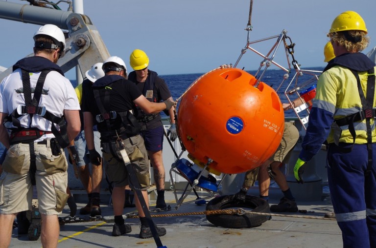 Crew and Scientists lower an Acoustic Doppler Current Profiler (ADCP) to the deck of the Falkor.