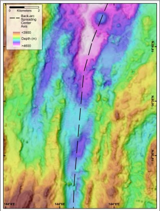 Map of a section of the Mariana Back-arc. The black dashed line traces the axis of spreading, which has created a valley up to 10 km wide in this location. This valley is one of our targets for the discovery of hydrothermal vents. 