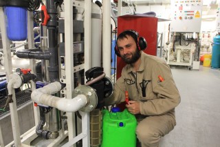Electro technical officer Todor Gerasimov works on fixing a fresh water flow sensor.