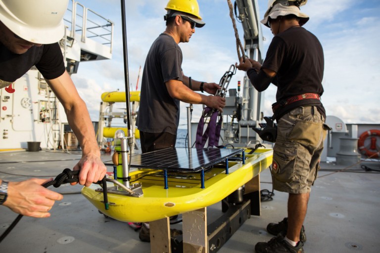 Oliver Hurdwell, Jeffery Oshiro, and Archel Benitez ready the glider to be launched into the water using Falkor's aft deck cranes.