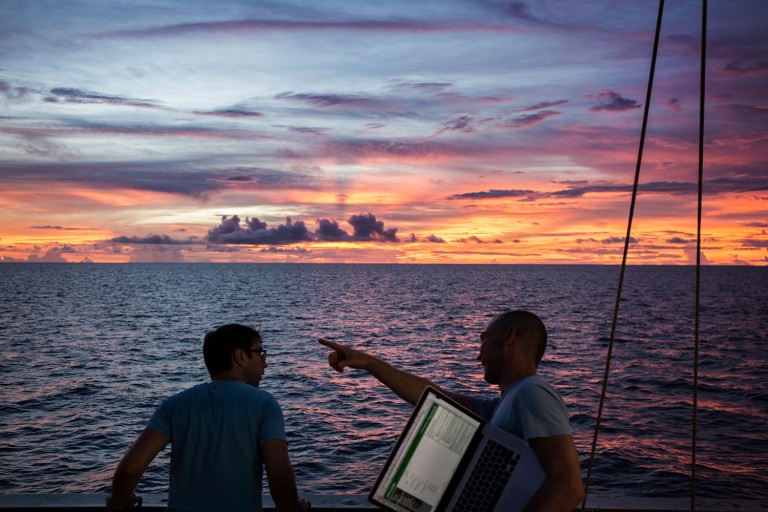 Scientists take a break from their labs to enjoy a spectacular sunset off the aft deck of Falkor.