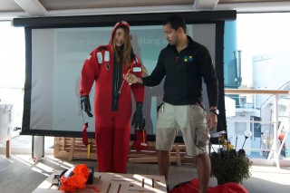 Graduate student Arielle Anderson dons an immersion suit as safety officer Thiago Da Silva conducts a mandatory training for the science team.