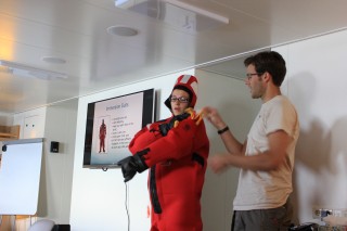 Safety Officer Oliver Hurdwell shows studetnt opportunties participant Julianna Diehl how to put on an emersion suit during safety training. 