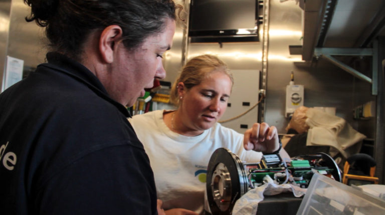 Marine Technician Deborah Smith and Oceanographer Mariana Ribas take a look at one of the components of the drifting buoy. Seawater entered the instrument so they are finding a way to repair the damage and get the buoy back to work.