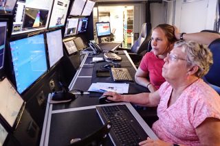 Jena Kline is a teacher from ‘Iolani School currently onboard Falkor to learn about multibeam mapping. Joyce Miller teaches her how to clean noise out of data in order to render more reliable maps.