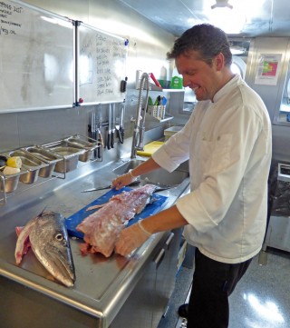 Chef Carlos Waihrich prepares the barracuda in the galley. 