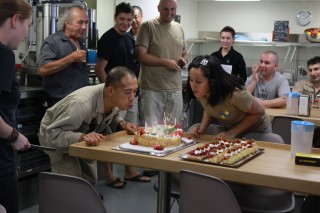 Leny Pancito and Ramon Tabaque blow out candles on their birthday cake in the ship's mess.