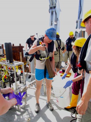 WHOI Specialist Casey Machado holds a full sediment core collected from the free vehicle coring respirometer. 