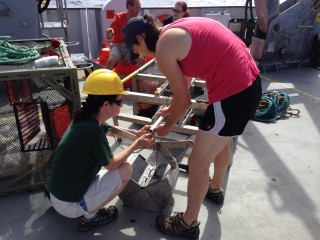 Scientist Patty Fryer and WHOI Specialist Casey Machado attach the grab sampler to the new arm on the Wee Trap. 