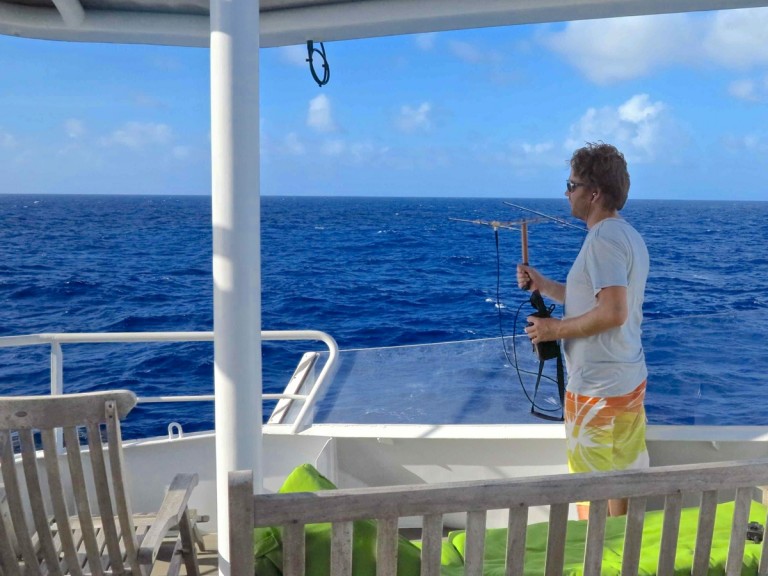 Dieter Bevans scans the horizon and listens intently for any acoustic signals from the landers with a radio finder. 