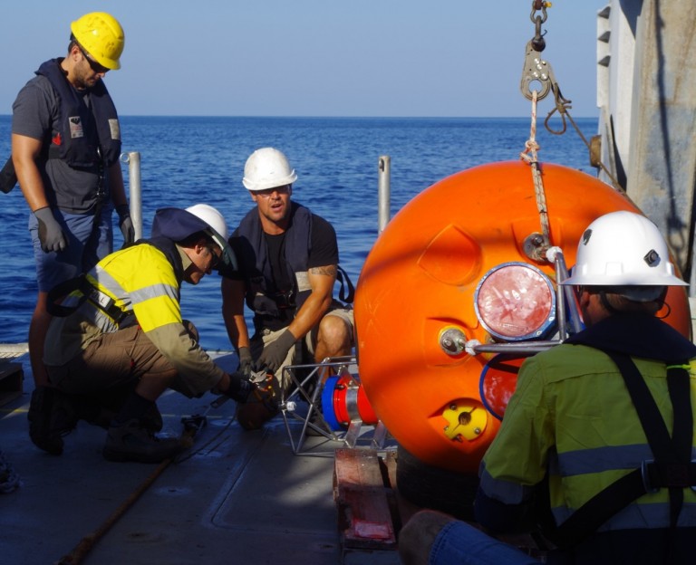 The moorings team and members of Falkor’s deck team prepare a deep Acoustic Doppler Current Profiler to measure currents in the deep channel.