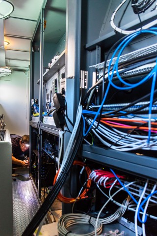 Workers have to fit in tight places to correctly and efficiently wire the video matrix system and Control Room on Falkor.