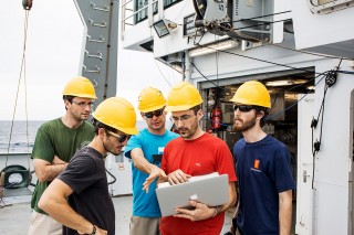 Scientists on Falkor's deck react to information and readings from AUV’s sensors being sent onto their laptops. 