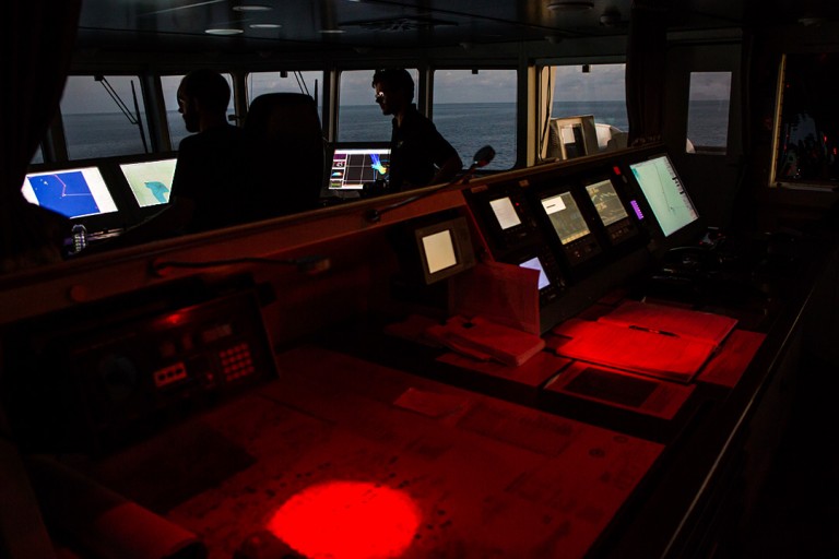 As night begins to fall, Chief Officer Allan Doyle and Second Officer Oliver Hurdwell turn on red lights on the bridge to preserve night vision. 