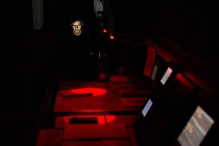 Second Officer Oliver Hurdwell checks a laptop before his shift begins. The red lights on the bridge are to preserve night vision. 