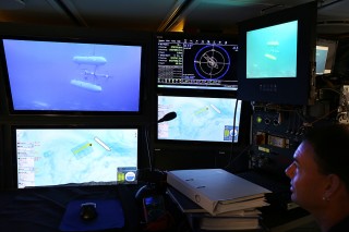 Matt Edmunds watches the Sirius AUV in the control center of Falkor from a feed coming in live from a ROV launched from the ship. Other screens show tracking and location maps. 