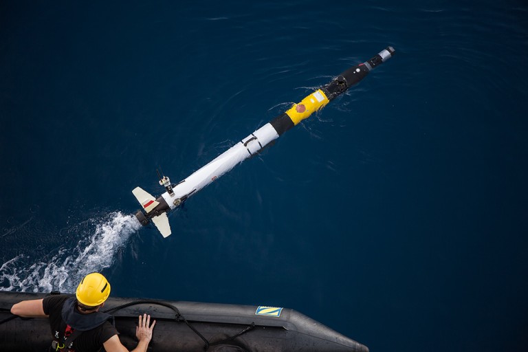 Andrew Durrant lets go of the Iver AUV during a ballast calibration. Its transceiver can be seen near its back fins and thruster.