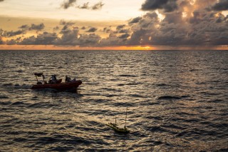 After being launched, the Float portion of the Wave Glider trails Falkor as a small boat watches in case support is needed.