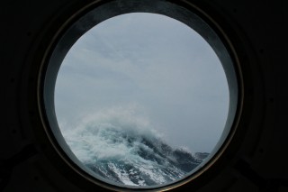 Rough seas are visible from the port hole in the mess.
